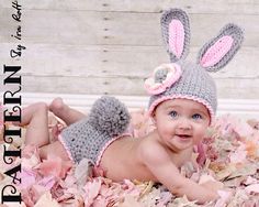 a baby wearing a knitted bunny hat and diaper laying on top of pink flowers