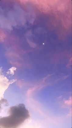 an airplane is flying in the sky with clouds and a half moon behind it at dusk