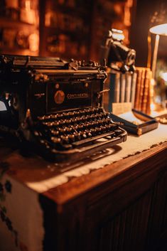 an old fashioned typewriter sitting on top of a wooden desk next to a lamp