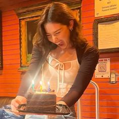 a woman holding a cake with lit candles