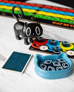 a black cat figurine sitting on top of a table next to a game board