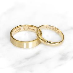 two gold wedding rings sitting on top of a white marble surface with the words always & forever engraved on them