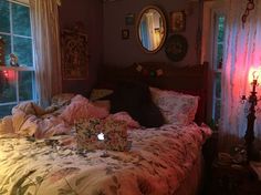 an unmade bed with flowers on it in a bedroom next to two large windows