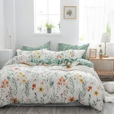 a bedroom with white walls and flowers on the bedspread, pillows and blankets