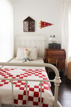 a white bed with a red and white checkered bedspread