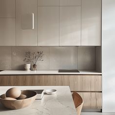 a modern kitchen with white cabinets and marble counter tops, including a wooden bowl on the table