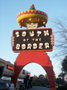 a sign that says south of the border with a large sombrero on top