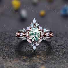 a ring with an oval shaped green stone surrounded by small white and pink stones on top