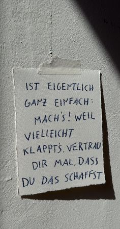 a piece of paper with writing on it hanging from the side of a white wall