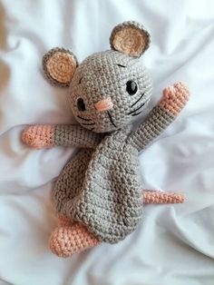 a crocheted mouse laying on top of a bed