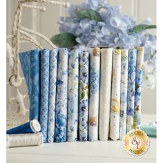 a stack of blue and white fabric sitting on top of a table next to flowers