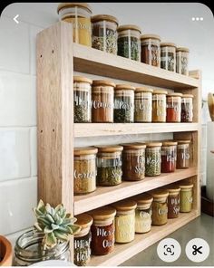 a wooden shelf filled with lots of different types of spices and jars on top of it