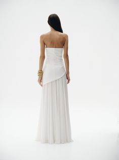 the back of a woman in a white dress, with her hands on her hips