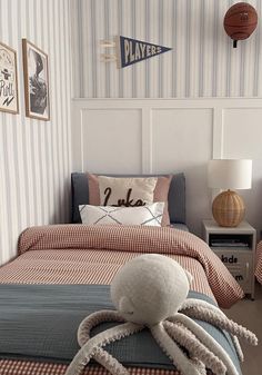 an octopus stuffed animal sitting on top of a bed in a room with striped walls