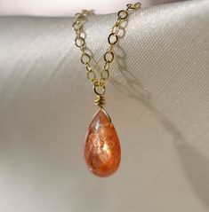 "Natural, Genuine Sunstone Necklace First discovered in Norway, Sunstone gets its shimmering nature from tiny pieces of Hematite. It is believed that this gem carries the uplifting energy of the sun, and is perfect for those who are stuck in a rut or need a little reminder to live and enjoy life. It is a stone of empowerment that helps your true self shine, while encouraging joy, passion, and good fortune. This necklace is handmade with a genuine, natural Sunstone teardrop that is smooth polishe Gold Wire Wrapped Drop Necklace As Gift, Gold Wire Wrapped Drop Necklace For Gift, Gold Wire Wrapped Drop Necklaces, Gold Wire Wrapped Drop Necklace, Orange Drop Jewelry For Gift, Gold Teardrop Drop Necklace With Natural Stones, Gold Wire-wrapped Drop Necklace As Gift, Natural Stone Pear-shaped Jewelry Gift, Pear-shaped Natural Stones Jewelry For Gifts