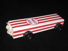 a red and white striped box with popcorn on the side sitting on a black surface