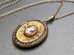 "Vintage antique locket shell cameo Etruscan locket black enamel locket antique jewelry gift for her  Details: 10k Gold filled Victorian locket pink and white cameo Gold filled metal with gold filled chain C. 1930s Measurements: Locket is approx 1 3/4\" with bale by 1\" Chain is approx 18\" long Condition: Excellent vintage condition with lightest signs of age-appropriate use and wear. Locket does have some wear to the enamel, opens and closes securely.  Includes 2 frames and plastics. Have a qu Enamel Locket, Victorian Locket, Antique Locket, Victorian Gold, Gold Locket, Antique Necklace, Locket Necklace, Gold Filled Chain, Black Enamel