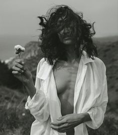 a man with long hair holding a flower