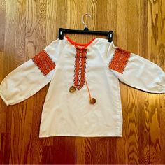 A Vintage Ukrainian Vyshyvanka Top, Crafted With Traditional Ukrainian Cross Stitch Embroidery. This Handmade Beauty Showcases Intricate Patterns And Vibrant Colors That Are True To The Rich Ukrainian Heritage. Complete With Pom-Pom Accents, This Top Is A Unique And Stylish Piece That Effortlessly Blends Tradition And Fashion. Own A Piece Of Ukrainian Culture And Make A Fashion Statement With This Timeless Treasure! Ukrainian Cross Stitch, Ukrainian Vyshyvanka, Ukrainian Culture, Handmade Beauty Products, Stitch Embroidery, Timeless Treasures, Intricate Patterns, Orange White, Cross Stitch Embroidery