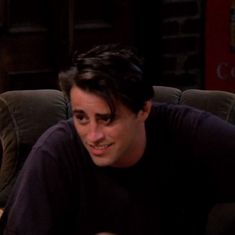 a man sitting on top of a couch in front of a table with a remote control