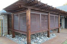 a wooden pergolated covered patio with rocks and gravel