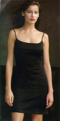 a woman in a short black dress posing for a photo with her hair blowing back