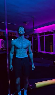 a man with no shirt standing on a skateboard in a room filled with neon lights