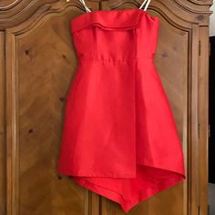 a red dress hanging on a wooden wardrobe