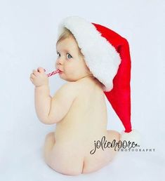 a baby wearing a santa hat chewing on a candy cane