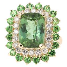 A unique beauty that is sure to be a rare and gorgeous design! This stunner has a gorgeous Rectangular/Cushion Cut leafy Green Tourmaline that weighs 7.90 Carats. Surrounding the Tourmaline are 20 Round Cut Diamonds that weigh 0.90 Carats with a clarity and color of SI1-H. Further its embellished with 20 Tsavorites that weigh 1.69 Carats with a clarity and color of SI1-H. The total carat weight of the ring is 10.49 Carats. The measurements of the rectangular cushion cut tourmaline are 9 mm x 14 mm. The ring is made in 14 Karat Yellow Gold and weighs approximately 8.2 grams. It is a size 7 and can be re-sized at no additional charge. Chrome Tourmaline, Yellow Gold Cocktail Ring, Sapphire Cocktail Ring, Rectangular Cushion, Vintage Cocktail Ring, Vintage Jewelry Art, Flowers Petals, Gold Cocktail Ring, Contemporary Ring