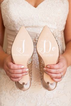 a bride holding her wedding shoes with i do written on them