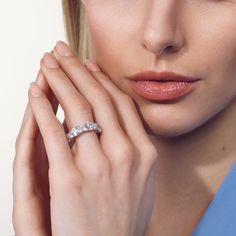 a close up of a woman wearing a ring and holding her hand near her face