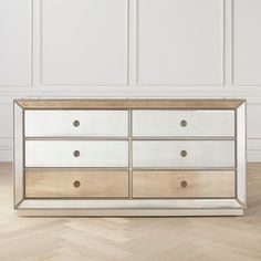 a white and gold dresser sitting on top of a wooden floor next to a wall