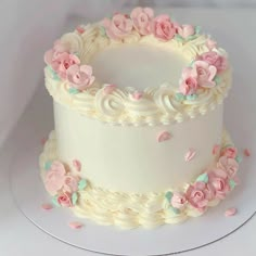 a white cake with pink and blue flowers on it's side, sitting on a plate