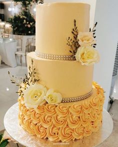 a three tiered cake decorated with yellow flowers and diapaste trimmings