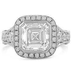 Looking for an affordable large diamond ring? This 8mm Asscher cut engagement ring is just the thing to consider. The center is a sparkling forever one Charles and Colvard Authentic moissanite and is surrounded by a carat of round cut pave style natural diamonds.  
   This is a custom made to order item and can be modified to fit your needs. Please contact us for special customization 
     MAIN GEM  Gem: Moissanite 
 Shape: Asscher 
 Carat Weight: 
 Size: 8mm 
 Color: Forever One 
 SIDE STONES 
 Gem: Natural Diamonds 
 Shape: Round 
 Carat Weight: 1.00ctw 
 ADDITIONAL INFORMATION 
 Style #: A41M 
Also available with contouring matching band Timeless Asscher Cut Diamond Ring With Halo Setting, Asscher Cut Lab Grown Diamond Promise Ring, Luxury Moissanite Halo Ring For Anniversary With Asscher Cut, Luxury Moissanite Halo Ring For Anniversary, Asscher Cut, Moissanite Asscher Cut Halo Ring For Anniversary, Moissanite Asscher Cut Ring With Halo Setting, Fine Jewelry Moissanite Asscher Cut Halo Ring, Fine Jewelry Moissanite Halo Ring Asscher Cut, Moissanite Asscher Cut Diamond Rings