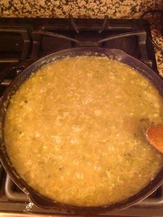 a pot on top of a stove with a wooden spoon in it and some food inside