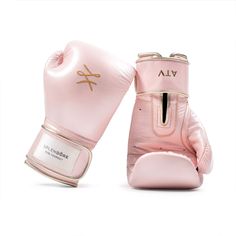 two pink boxing gloves sitting side by side on top of each other, one has a gold logo on it