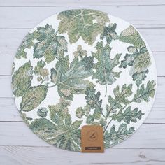 a white plate with green leaves on it sitting on a wooden table next to a tag