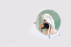 a woman with a towel on her head taking a photo in a mirror