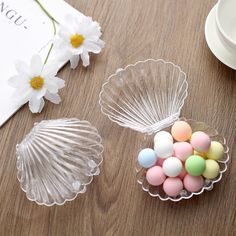 three glass dishes with candy in them sitting on a wooden table next to a flower