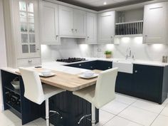 a kitchen with white and blue cabinets, black counter tops, and an island in the middle