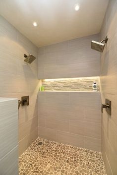 a walk in shower sitting next to a tiled floor and wall with lights above it