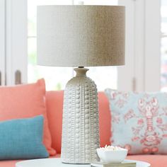 a table with a lamp on top of it next to a couch in a living room