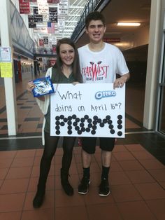 two people standing next to each other holding a sign