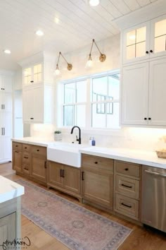 a large kitchen with white cabinets and wood flooring, along with a rug on the floor