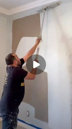 a man is painting the walls in his house with paint rollers and a tape measure