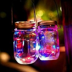 two mason jars with lights hanging from them