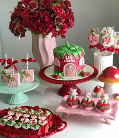 a table topped with cakes and cupcakes covered in frosting next to a vase filled with flowers