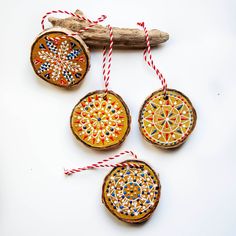 three wooden ornaments hanging from a branch with red and blue twine on it's ends